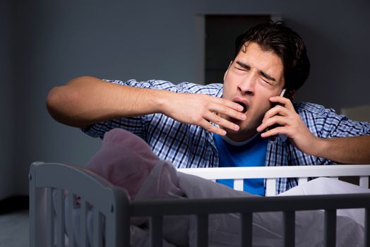 Young father dad sleeping while looking after newborn baby