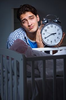 Young father dad sleeping while looking after newborn baby