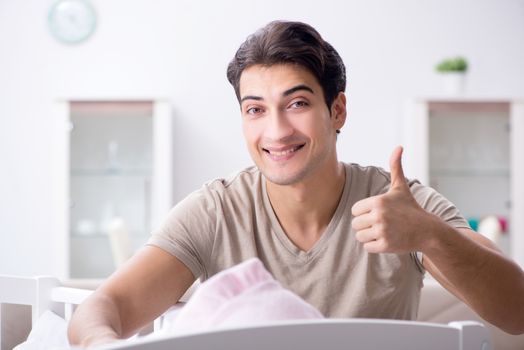 Young father enjoying time with newborn baby at home