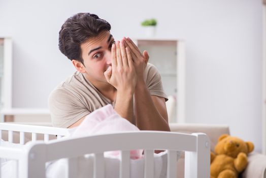 Young father enjoying time with newborn baby at home