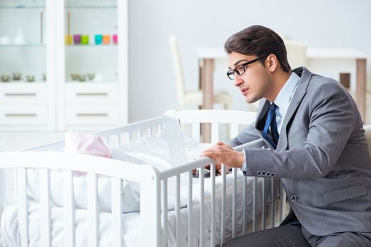 Young businessman trying to work from home caring after newborn baby