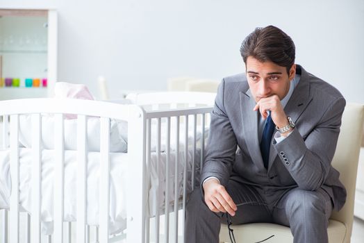 Young businessman trying to work from home caring after newborn baby