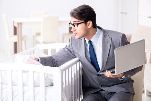Young businessman trying to work from home caring after newborn baby