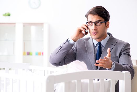 Young businessman trying to work from home caring after newborn baby