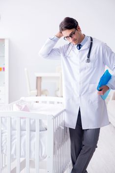 Man male pediatrician near baby bed preparing to examine