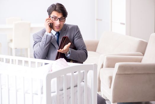 Young businessman trying to work from home caring after newborn baby