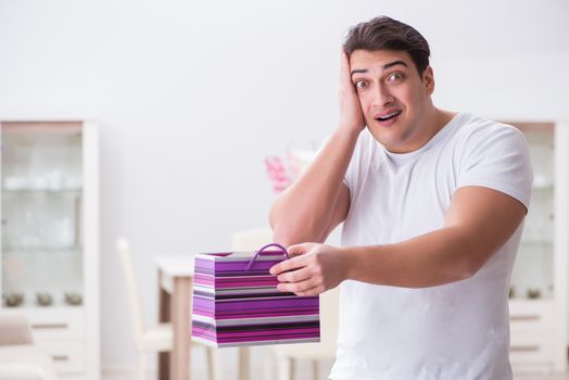 Young man with gift bag at home preparing suprise for wife