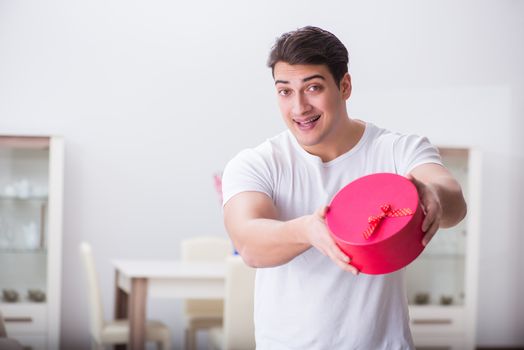 Young man with gift bag at home preparing suprise for wife