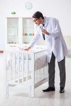 Man male pediatrician near baby bed preparing to examine