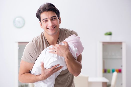 Young father enjoying time with newborn baby at home