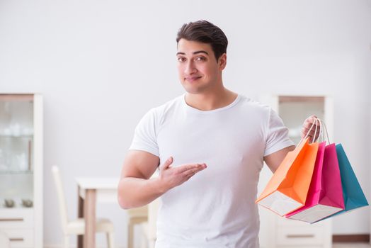 Young man with gift bag at home preparing suprise for wife