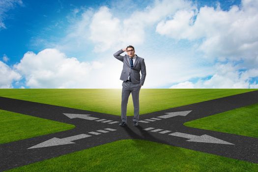 Young businessman at crossroads in uncertainty concept