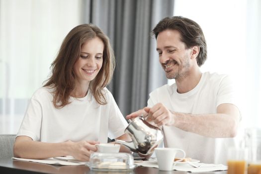 Husband pouring coffee early morning breakfast routine in home living room lounge