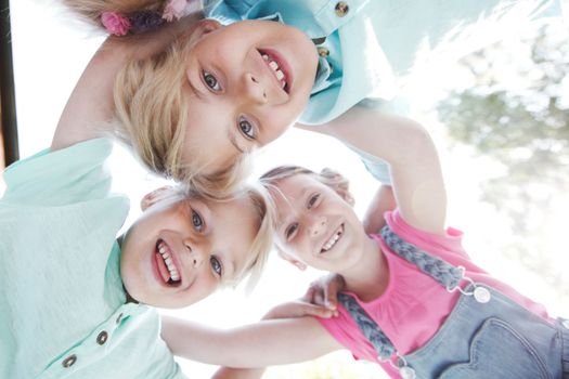 Group of three children friends outdoors looking down smiling