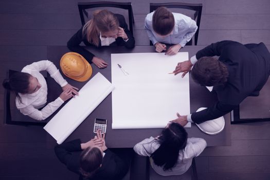 Top view of people around table in construction business meeting blank blueprint paper with copy space for text