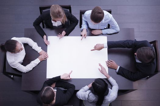 Group of business people around blank paper, top view, man pointing at white copy space, new project concept