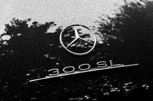 LONDON, UK - CIRCA SEPTEMBER 2011: Black and white closeup shot of Mercedes 300SL logo. Raindrops on the bodywork.