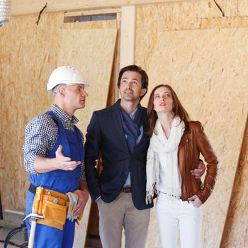 Foreman or achitect engineer shows future house to happy couple