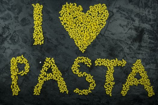 Pasta in the shape of a heart on a black background.