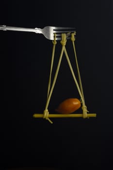 Spaghetti on a fork in front of black background. Swing from spaghetti.