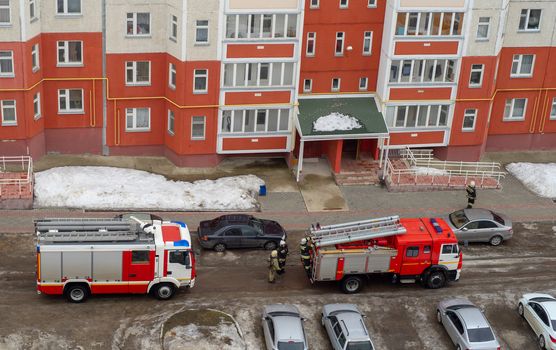 Fire engine in the courtyard of a multi-storey residential building in winter.