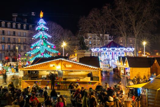 BAYONNE, FRANCE - DECEMBER 28, 2019: The Christmas market at night with the carousel and a Christmas tree carousel