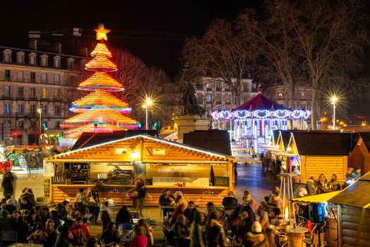 BAYONNE, FRANCE - DECEMBER 28, 2019: The Christmas market at night with the carousel and a Christmas tree carousel