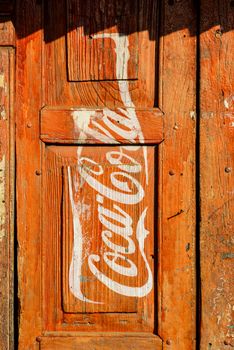 KATHMANDU, NEPAL - CIRCA JANUARY 2014: Vintage Coca-Cola advertisement painted on a red wooden door.