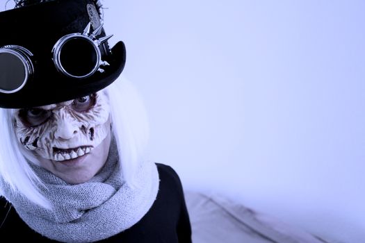 Woman with monster face and black hat wearing steampunk glasses. White hair.