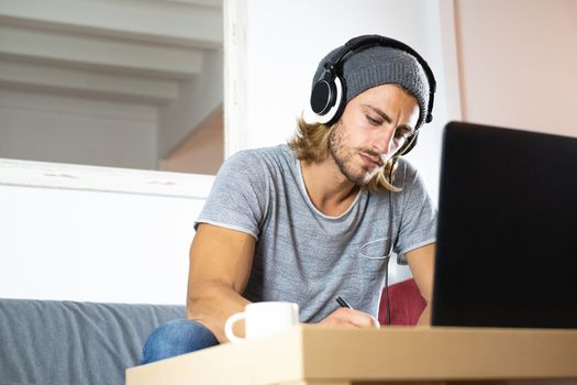 Handsome male businessman working on laptop with headphones from home