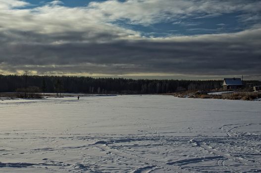 A house by a pond in winter in the snow. Life in nature by the water.