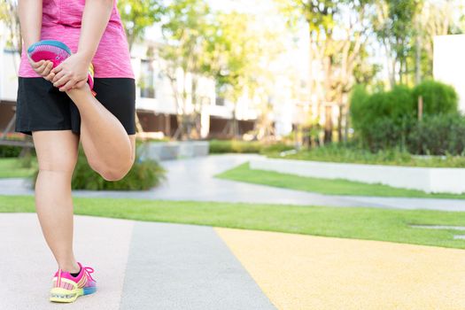 Female fatty runner athlete stretching legs before running in the park.