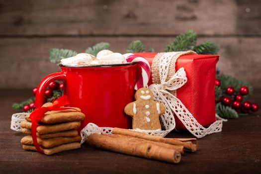 Cocoa in red mug with marshmallows and candy cane and Christmas fir tree on dark wooden background