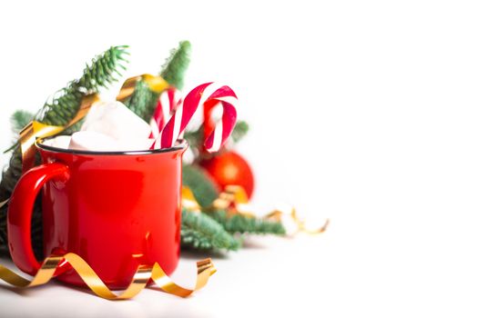 Cocoa in red mug with marshmallows and candy cane and fir tree branches and red and golden baubles and stars isolated on white background