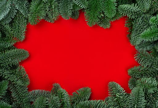 Christmas fir tree branches decor border frame on red background with copy space for text