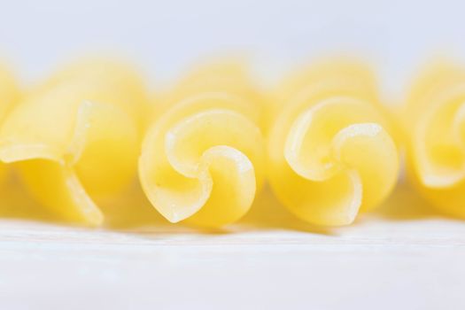Abstract Closeup view of raw pasta on wooden background.
