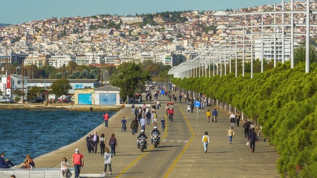 Unidentified persons with face protection walk on the pedestrian area of the city waterfront in Thessaloniki, Greece.