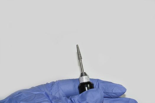 Milling cutter in a manicurist hand on a wight background. Manicure and pedicure professional tool.
