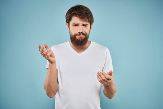 Man in white t-shirt lifestyle studio emotions facial expression blue isolated background. High quality photo