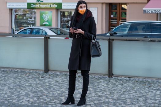11/16/2020. Czech Republic. A woman wearing a mask is waiting for a tram at Hradcanska tram stop during quarantine. This is a lockdown period in the Czech Republic due to the increase of COVID-19 infectious in the country. Hradcanska tram stop it is in Prague 6