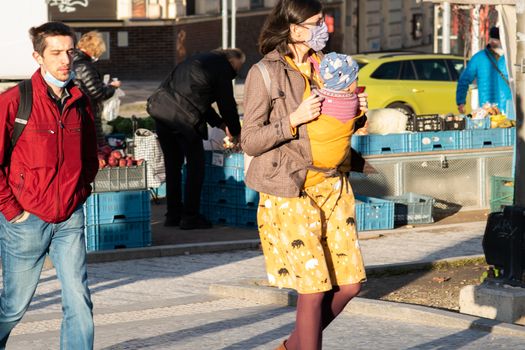 11/16/2020. Prague, Czech Republic. A mother is crossing the street with her small child close to Hradcanska tram stop during quarantine (she is wearing a mask). This is a lockdown period in the Czech Republic due to the increase of COVID-19 infectious in the country. Hradcanska tram stop it is in Prague 6