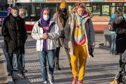 11/16/2020. Prague, Czech Republic. People wearing masks crossing the street close to Hradcanska tram stop during quarantine. This is a lockdown period in the Czech Republic due to the increase of COVID-19 infectious in the country. Hradcanska tram stop it is in Prague 6