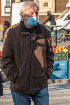 11/16/2020. Prague, Czech Republic. An old man is wearing masks while crossing the street close to Hradcanska tram stop during quarantine. This is a lockdown period in the Czech Republic due to the increase of COVID-19 infectious in the country. Hradcanska tram stop it is in Prague 6