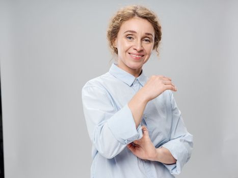 Elderly woman in a light shirt on a gray background smiling at the camera portrait