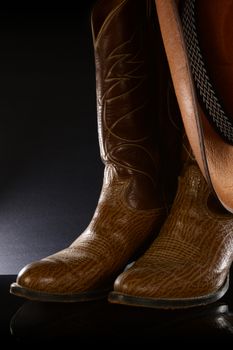 A pair of brown leather cowboy boots over a black background.