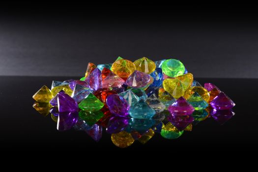 A pile of gemstone variations over a black reflective surface.