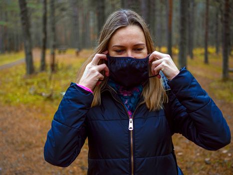 Beautiful european Women Wearing Protective Mask Outside Pretty young girl in medical black face mask in a forest. covid19 concept. modern reality. copy space. 2020, allergy. Autumn season. Copy space