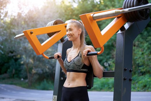 Sportive female training exercise machine outdoor gym summer park Middle age caucasian woman dressed sportswear workout outside on simulator sport ground. Healthy lifestyle concept