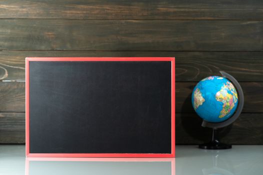 Chalkboard mock up frame and globe model on table near wood background in home