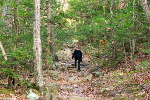 A Young Caucasian Man Wearing All Black Walking Up a Mountain Path